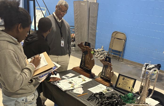  Mr. Davis with at recruiting fair speaking with an 8th grade male